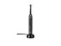 Brosse à dents électrique noire avec une tête ronde sur une base de chargement.
