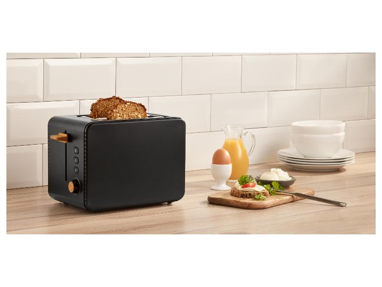 Grille-pain noir avec pain grillé, jus d'orange, œuf et petit-déjeuner dans une cuisine moderne.