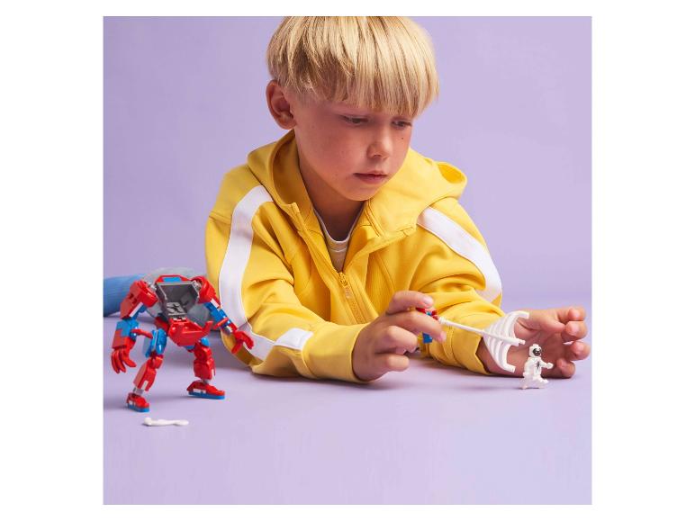 Un garçon joue avec un robot rouge et une figurine blanche sur un fond violet.