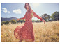 Une femme portant une longue robe rose à fleurs dans un champ.