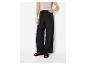 Femme en pantalon noir large et haut en crochet clair avec des sandales.