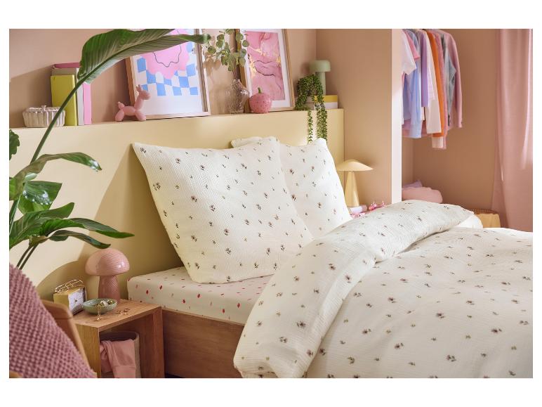 Chambre avec housse de couette florale, drap-housse fraise et objets décoratifs.