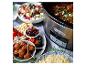 Un Crock-Pot avec un plat, servi avec une salade, du fromage, des olives et des boulettes de viande.