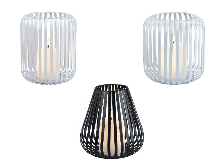 Trois lanternes avec bougies : deux blanches cylindriques et une noire en forme de goutte.