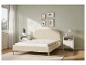 Un lit beige avec un matelas blanc dans une chambre lumineuse.