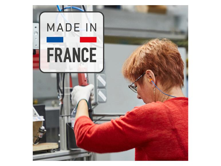 Femme travaillant en usine, avec un panneau 'MADE IN FRANCE' en arrière-plan.