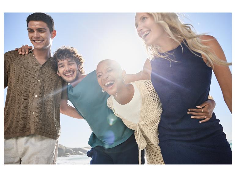 Amis souriants en vêtements décontractés près de l'océan.