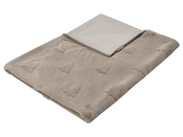 Couverture douce et beige avec motif de sapins de Noël en relief, pliée.