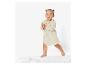 Bébé portant une robe beige et debout sur un tapis blanc.