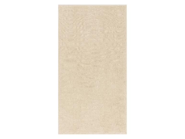 Serviette de bain beige clair, douce et moelleuse.