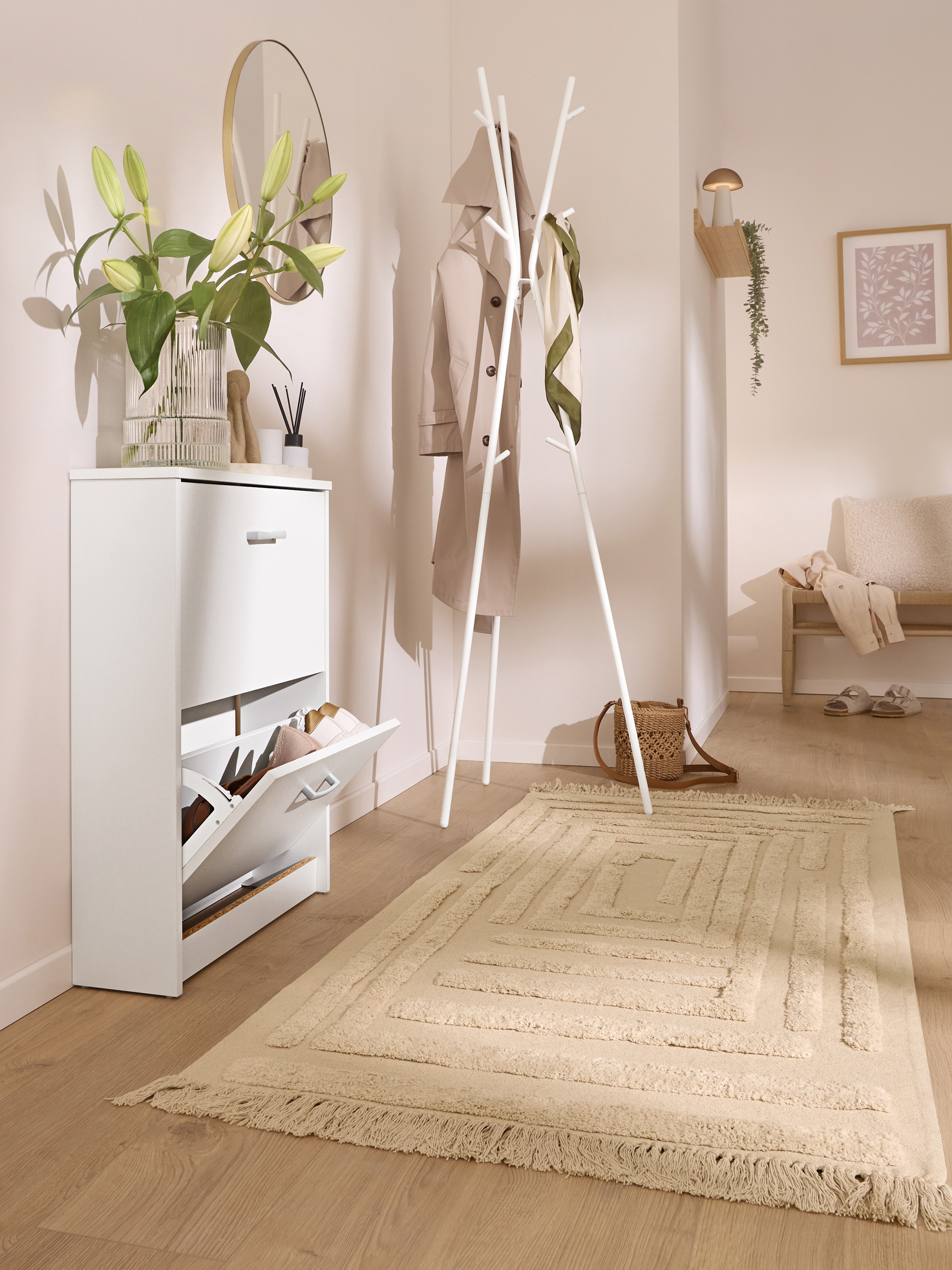 Entrée avec meuble à chaussures blanc, porte-manteau et tapis beige.