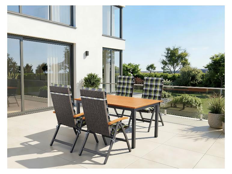 Ensemble de mobilier d'extérieur avec table et chaises sur une terrasse avec vue sur un jardin.