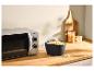 Un micro-ondes argenté et un bol à popcorn noir sur un comptoir en bois.
