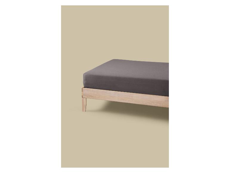 Lit en bois avec matelas gris et drap-housse.