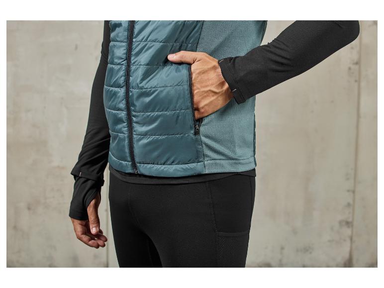 Un homme porte une veste matelassée bleue et un pantalon de jogging noir.