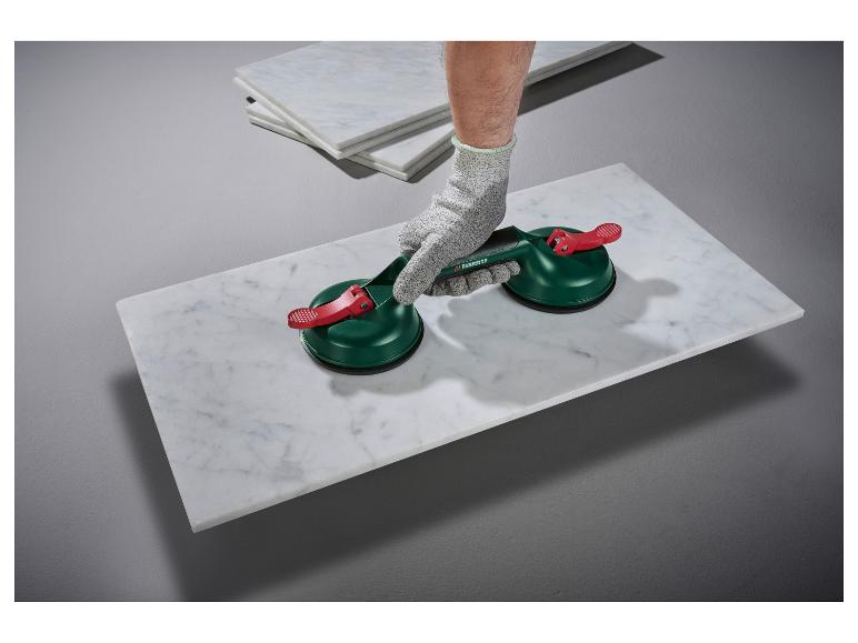 Ouvrier utilisant des ventouses pour soulever une dalle de marbre blanc.