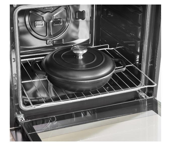 Cocotte en fonte noire avec couvercle à l'intérieur d'un four sur une grille.