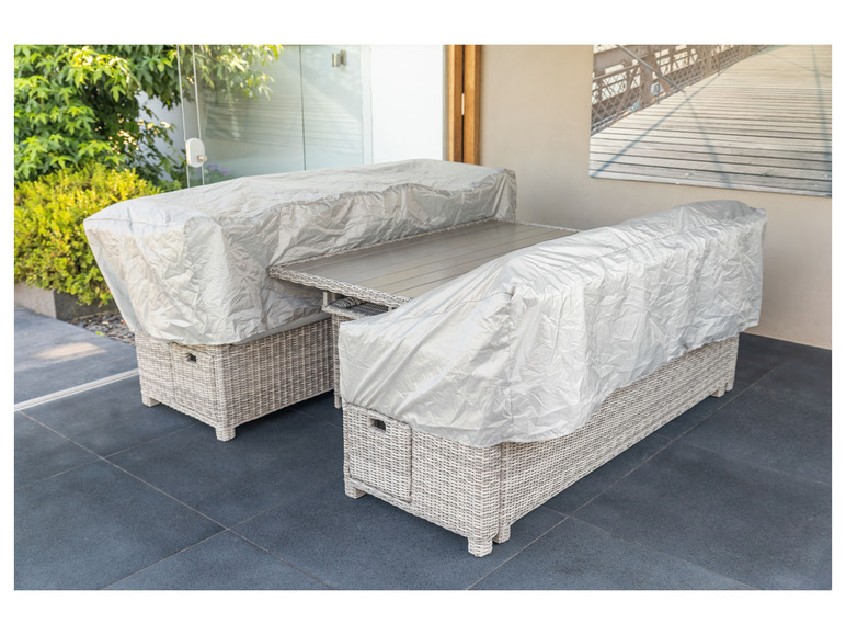 Un salon de jardin en osier avec une table et deux chaises, recouvert d'une housse de protection.