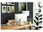 Bureau à domicile avec ordinateur, bureau en bois, chaise et plantes, devant un mur sombre.