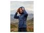 Femme aux cheveux roux bouclés portant une doudoune bleu marine dans un paysage montagneux.