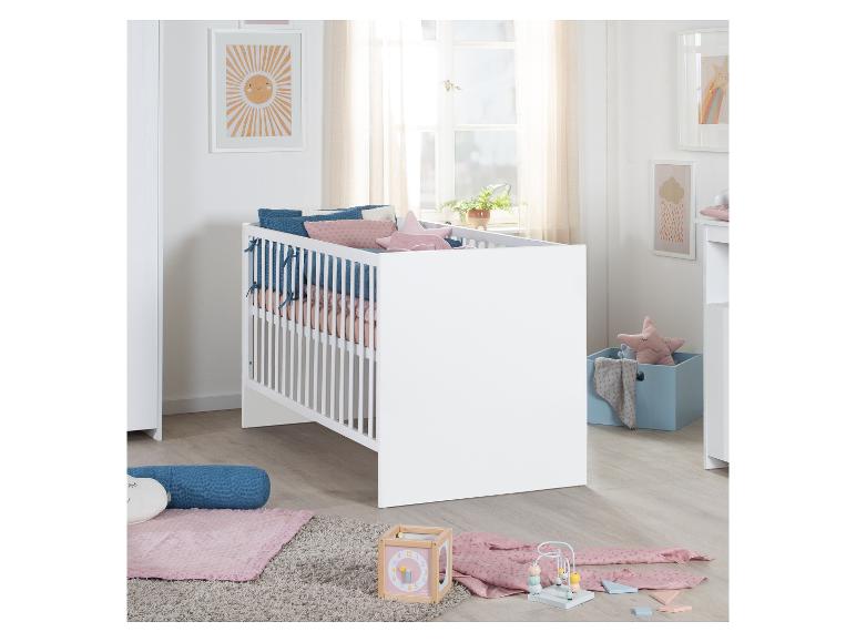 Lit bébé blanc avec oreillers roses et bleus, jouets et décorations murales soleil.