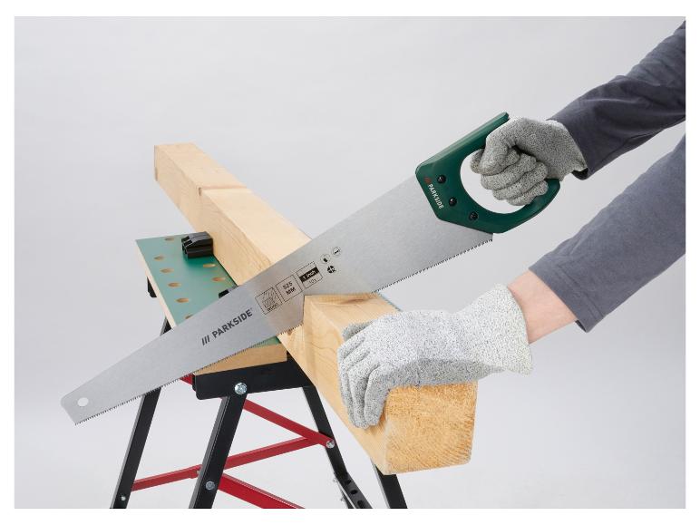 Scie à main coupant une planche de bois sur un établi, avec des gants de protection.