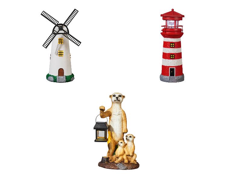 Un moulin à vent blanc, un phare rouge et une famille de suricates avec une lanterne.