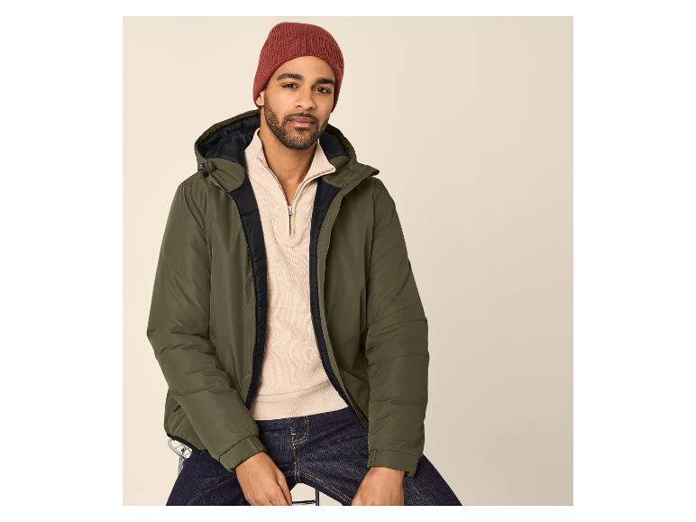 Homme en doudoune verte, pull beige à demi-zip, jean foncé et bonnet rouge.