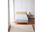Un lit avec un surmatelas bleu et un tapis blanc.