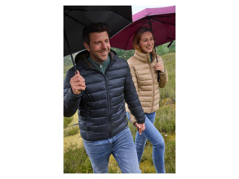 Couple souriant en doudounes tenant des parapluies noirs et fuchsia.