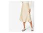 Une femme porte une jupe en satin beige et des baskets blanches.