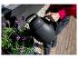 Personne arrosant des fleurs violettes avec un arrosoir noir.