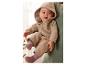 Un bébé dans une combinaison en laine beige à capuche est tenu par un adulte.