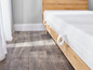 Un matelas blanc avec un cadre de lit en bois et un sol gris.