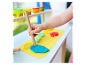 Un enfant joue avec de la pâte à modeler Play-Doh et des outils de modelage à une table en bois.