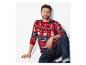 Homme en pull de Noël rouge avec des motifs de bonhomme de neige et de sapin, assis par terre.