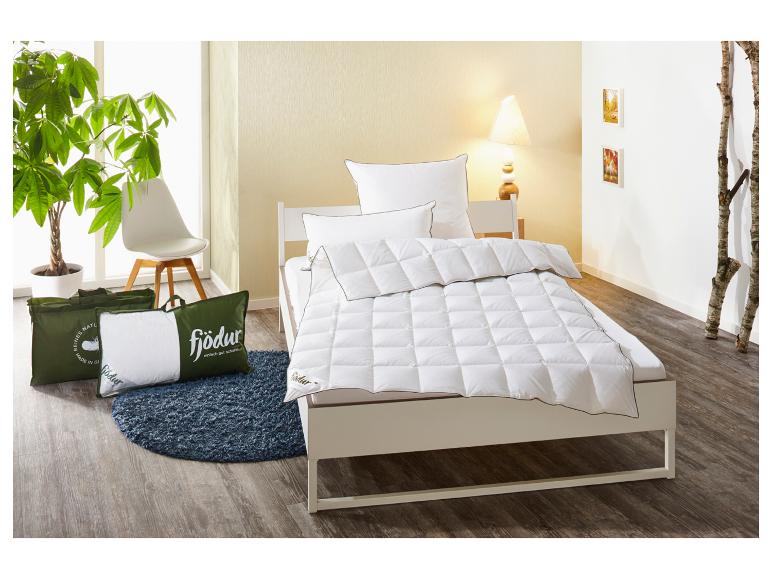 Couette et oreillers blancs Fjödur sur un lit, avec des oreillers dans des sacs verts au sol.