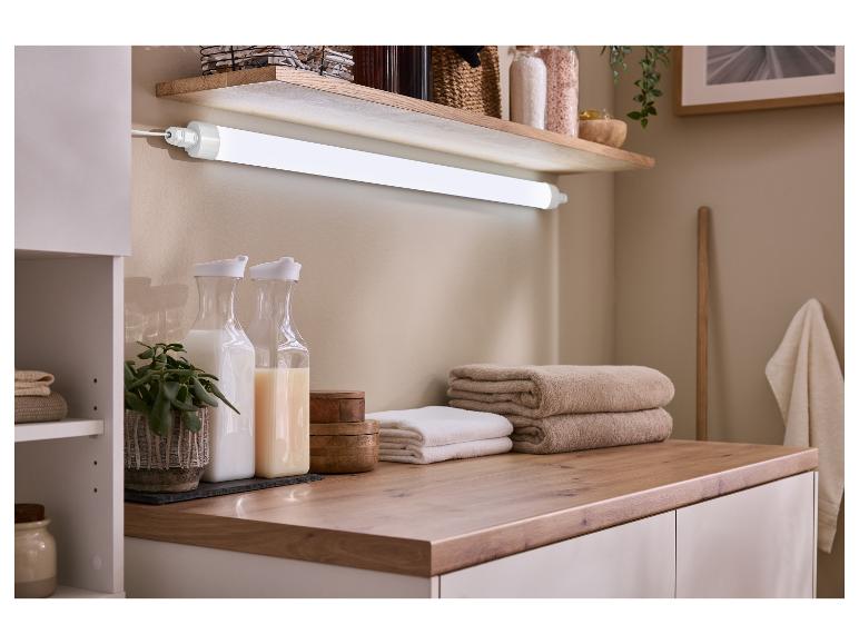 Aménagement de salle de bain avec étagère, éclairage, serviettes et bouteilles de rangement.