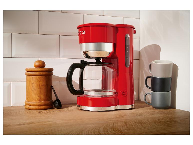 Cafetière rouge KitchenAid sur un comptoir en bois.