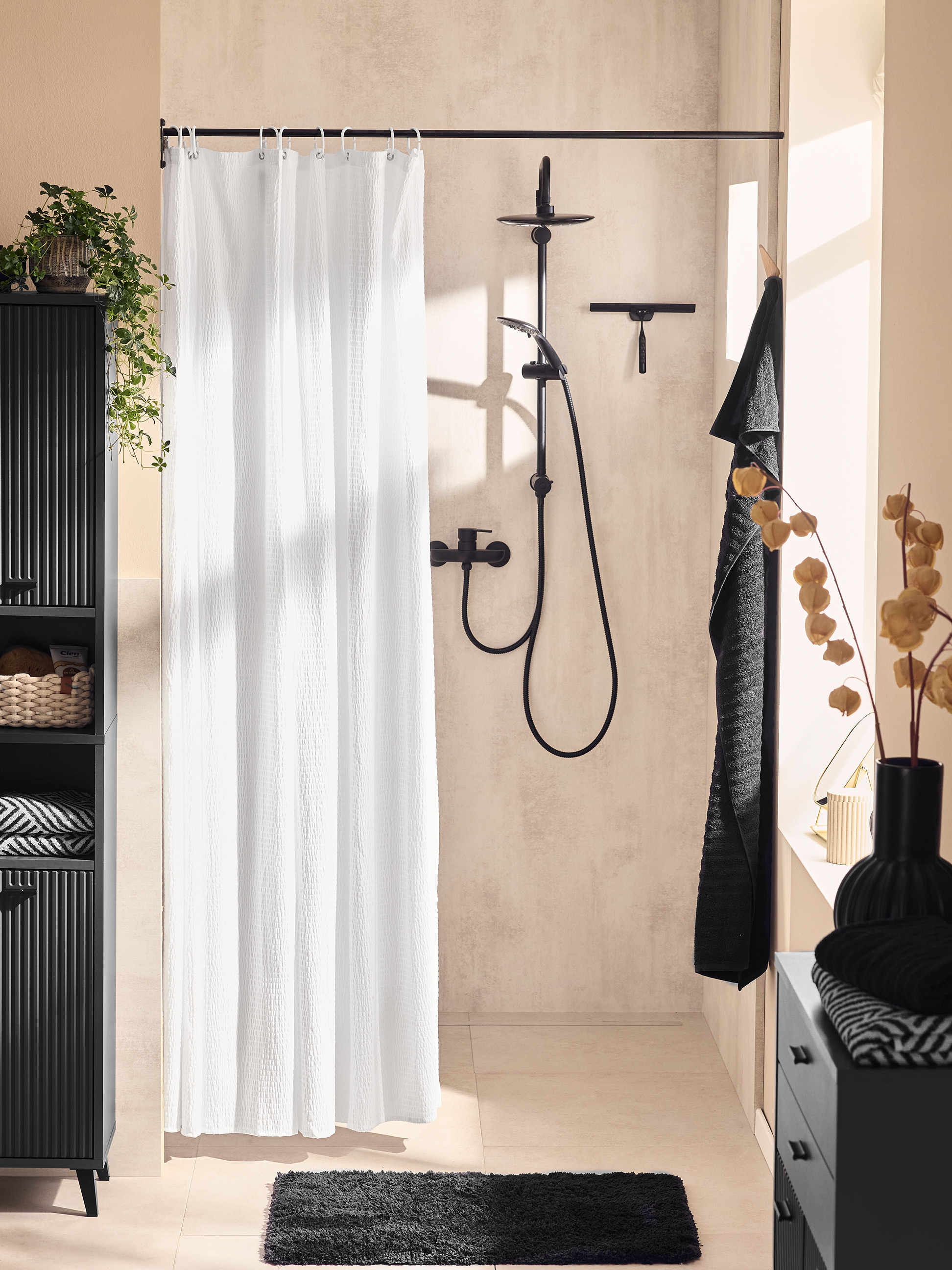 Salle de bain moderne avec meuble noir, rideau de douche blanc et tapis de bain noir.