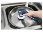 Une brosse électrique bleue est utilisée pour nettoyer une poêle dans un évier.