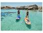 Deux personnes sur des paddleboards dans une eau turquoise avec une côte rocheuse en arrière-plan.