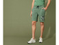 Un homme portant un short vert avec l'inscription 'United Club' et des baskets blanches.