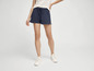 Une femme porte un t-shirt blanc et un short bleu.