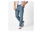 Homme en chemise beige clair et jeans bleus.