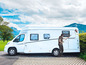 Une personne nettoie un camping-car blanc avec une brosse.