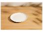 Assiette blanche vide sur une table en bois avec des ombres de feuilles