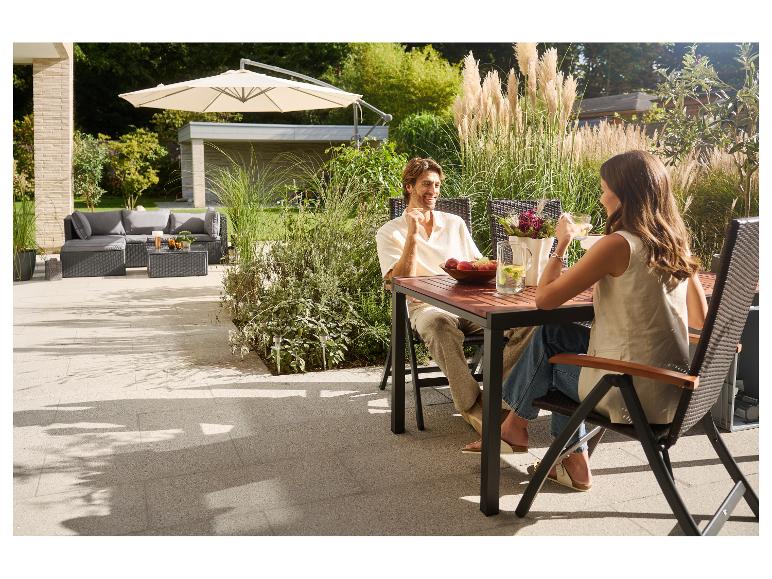Couple se relaxant sur une terrasse avec mobilier de jardin et parasol.