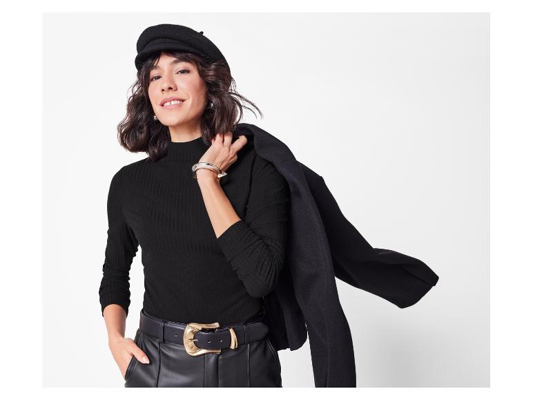 Femme élégante avec béret, pull côtelé et veste noire.