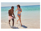 Un homme et une femme en maillot de bain courent dans l'eau sur la plage.